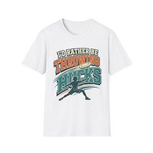 Puede incluir: Una camiseta blanca de manga corta con un estampado gráfico de una persona lanzando un disco volador. El texto I'D RATHER BE THROWING HUCKS aparece en letras de bloque naranjas y verde azulado, con líneas de movimiento alrededor.