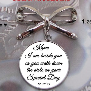 May include: Silver lapel pin with a bow and a round charm that reads "Know I am beside you as you walk down the aisle on your Special Day 12.30.25". The pin is 1.65 inches tall and 1.25 inches wide.