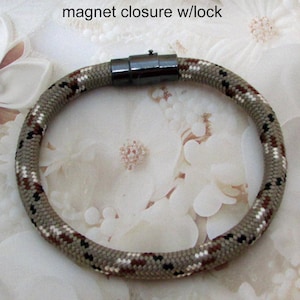 May include: Multi-color paracord bracelet, unisex, with a 1/4 inch diameter. The bracelet features a magnetic closure with a lock. The neutral colors of the bracelet will go with anything.