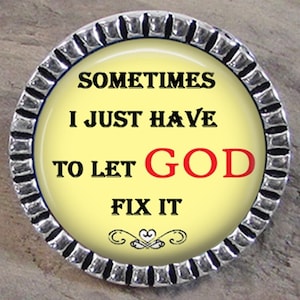May include: A silver pin with a yellow background and black text that reads 'Sometimes I just have to let GOD fix it.' The pin has a silver clutchback on the back side.