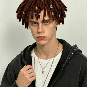 May include: A dark brown wig with short, textured dreadlocks adorned with small, decorative orange and white cylindrical beads. The hair is styled in a layered cut that frames the face, featuring a dense, uniform distribution of locks throughout.