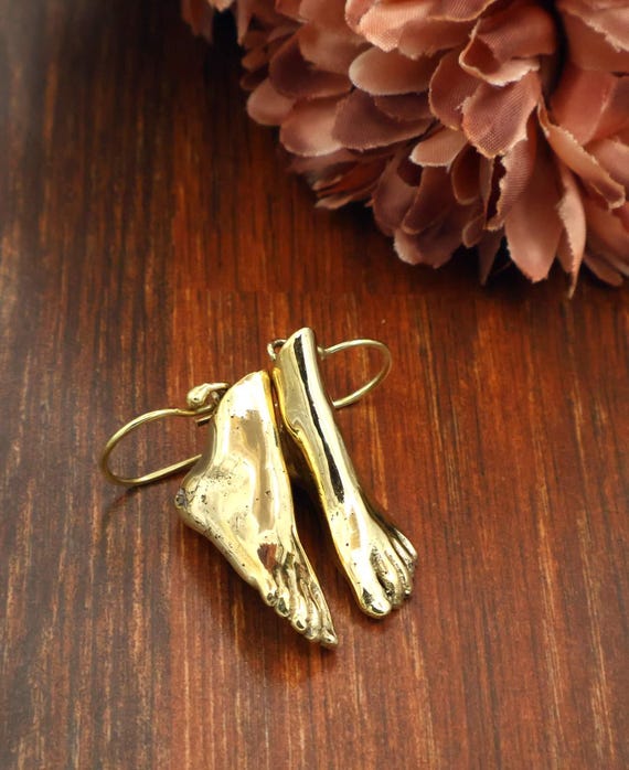 Tiny sculpted gold feet dangling from your ears — surrealist body-part jewelry that's equal parts Dalí and street-style statement.
