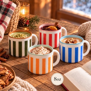 May include: Four ceramic mugs with vertical stripes in green, red, orange, and blue, each with a capacity of 8oz. The mugs are filled with various beverages topped with whipped cream, nuts, or fruit slices, arranged on a wooden surface.
