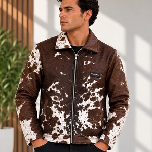 May include: A long-sleeved jacket featuring a brown and white cow print pattern, a classic collar, and a full-length silver-toned front zipper. The garment includes a small black rectangular label on the chest with the text Wesbro Wear.