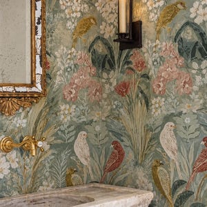 May include: A stone sink with a brass faucet, a gold-framed mirror, and a wall-mounted candle sconce against wallpaper featuring a green botanical pattern with various birds and flowers in shades of white, pink, red, and muted gold tones.