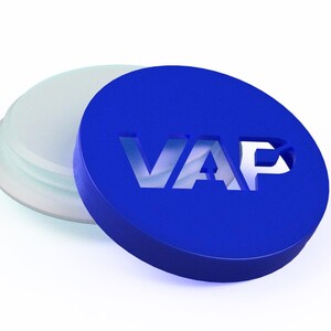 以下が含まれることがあります： VAPという切り抜き文字が施された円形の青い蓋。半透明の白い円形のベースから少しずらして配置されています。蓋は滑らかで無地の青い表面をしており、文字は切り抜かれたネガティブスペースによって明確に定義されています。