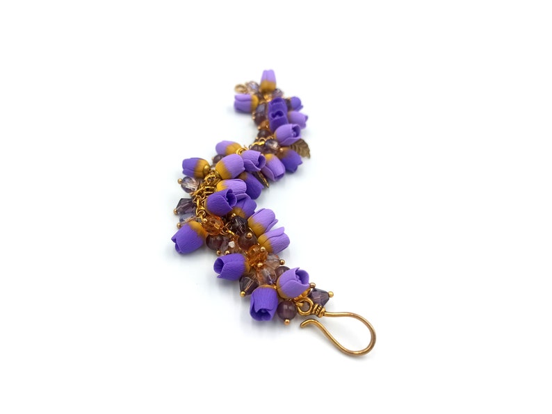 May include: A purple and gold bracelet with small flower charms and clear beads.