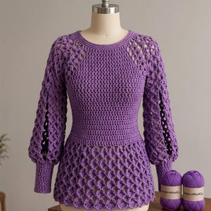 May include: A long-sleeved purple crochet sweater featuring a solid bodice, a lattice-patterned peplum hem, and matching lattice-patterned sleeves with ribbed cuffs. Two skeins of matching purple yarn with labels reading PatternPearlCo sit nearby.