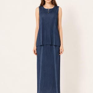 May include: A sleeveless dark blue two-piece set consisting of a round-neck top with two buttons at the neckline and a matching long skirt. Both pieces feature a fine vertical pleated texture throughout the fabric, creating a uniform appearance.