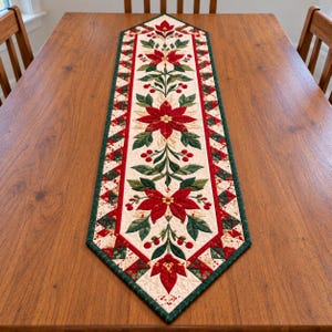 Könnte beinhalten: Ein gesteppter Tischläufer mit einem cremefarbenen Mittelteil, das ein wiederkehrendes Muster aus roten Weihnachtssternen, grünen Blättern und roten Beeren zeigt. Der Läufer ist mit einem geometrischen Muster aus dreieckigen Quiltblöcken umrandet.