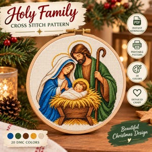 May include: A circular wooden embroidery hoop containing a cross stitch pattern of the Holy Family. The design features Mary in a blue veil, Joseph in a green robe holding a staff, and the infant Jesus in a manger. Text reads Holy Family.