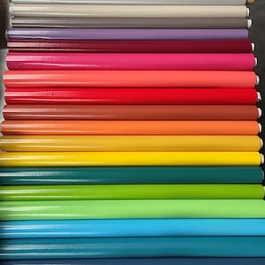 Peut inclure: Une collection de vingt et un rouleaux cylindriques de matériau lisse et de couleur unie empilés horizontalement. Les couleurs incluent l'or, le noir, le gris, le blanc, le beige, le marron, le violet, le bordeaux, le rose, le corail, le rouge, l'orange, le jaune, le sarcelle, le vert lime, le vert et le bleu.