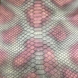 May include: A textured material featuring a repeating diamond-shaped scale pattern in shades of pink, grey, and white. The surface displays a central vertical column of larger, elongated scales flanked by smaller, uniform scales across the entire area.