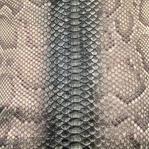 May include: A textured material featuring a repeating pattern of overlapping scales in shades of gray, beige, and dark brown. A central vertical column of larger, darker, rectangular scales runs down the middle, flanked by smaller, rounded scales.