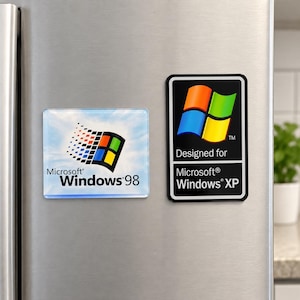 Peut inclure: Deux aimants rectangulaires présentant des logos de systèmes d'exploitation classiques. L'aimant de gauche affiche le logo Microsoft Windows 98 sur un fond de ciel bleu. L'aimant de droite est noir avec le logo Windows XP et le texte Designed for Microsoft Windows XP.