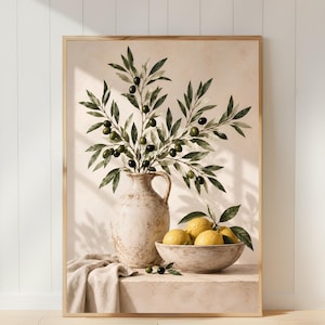 May include: A framed wall art print featuring a beige ceramic pitcher filled with olive branches and dark green olives. Beside the pitcher sits a shallow bowl containing four yellow lemons with green leaves, all set on a textured beige surface.