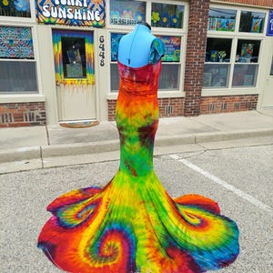 Puede incluir: Un vestido largo y fluido de tie-dye con una falda de estilo sirena. El vestido es una mezcla de colores brillantes, incluyendo rojo, naranja, amarillo, verde, azul y morado. El vestido est&aacute; hecho de una tela suave y el&aacute;stica y tiene un ajuste c&oacute;modo.