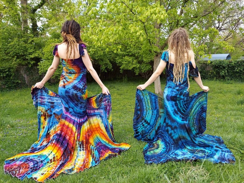 Puede incluir: Dos personas vistiendo largos vestidos de tie-dye con un patr&oacute;n colorido y arremolinado. Los vestidos tienen un corpi&ntilde;o ajustado y una falda larga y fluida.