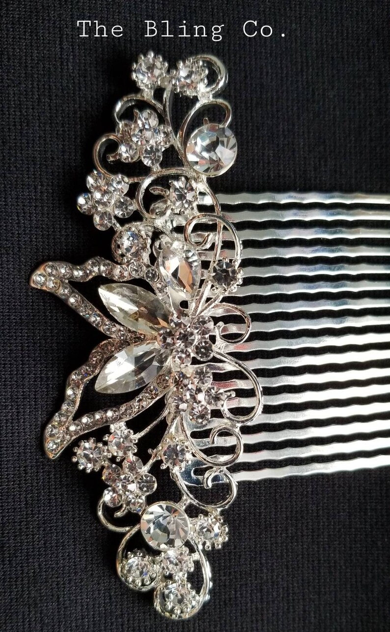 May include: Silver hair comb with a decorative design of a butterfly with clear rhinestones. The comb has a silver finish and is adorned with sparkling crystals.