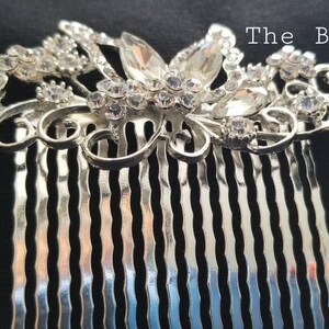 May include: Silver hair comb with a decorative design of a butterfly with clear rhinestones. The comb has a silver finish and is adorned with sparkling crystals.