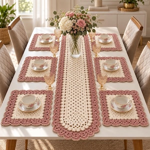 Peut inclure: Un ensemble de table comprenant un long chemin de table en crochet crème et vieux rose avec quatre sets de table rectangulaires assortis. Chaque set accueille une tasse à thé en porcelaine blanche à motif floral et un verre.