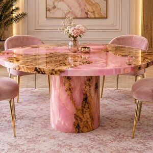 May include: A round dining table featuring a polished surface of pink resin and natural wood burl, supported by a cylindrical base of matching pink resin and wood. Four upholstered pink velvet chairs with gold metal legs surround the table.