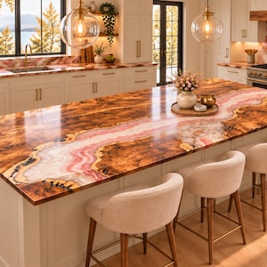 May include: A kitchen island featuring a polished countertop with a central vein of pink and white stone surrounded by dark brown wood grain patterns. The island base is off-white with three upholstered stools with wooden legs positioned in front.