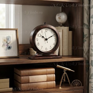 May include: A round analogue table clock with a dark brown wooden frame and a white face featuring black numerals and hands. The clock sits on a rectangular wooden base and is positioned on a shelf alongside books and a small brass telescope.