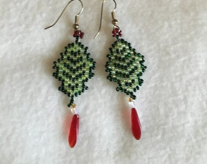 This pattern is my holly leaf. You will love wearing this earring because it has a red dagger glass bead hanging off the bottom.