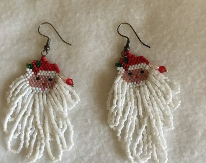 This pair of christmas earrings are santa's with a long flowing white beard. He also has a holly leaf in his hat.