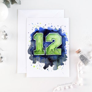 May include: Watercolor greeting card featuring the number 12 in green, with a cityscape silhouette and a star. The number is set against a dark blue and green watercolor splash background. The card is on a white background.