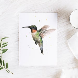 May include: Watercolor painting of a hummingbird in flight with a green and brown body, red throat, and a long, thin beak. The background is white with scattered watercolor dots.