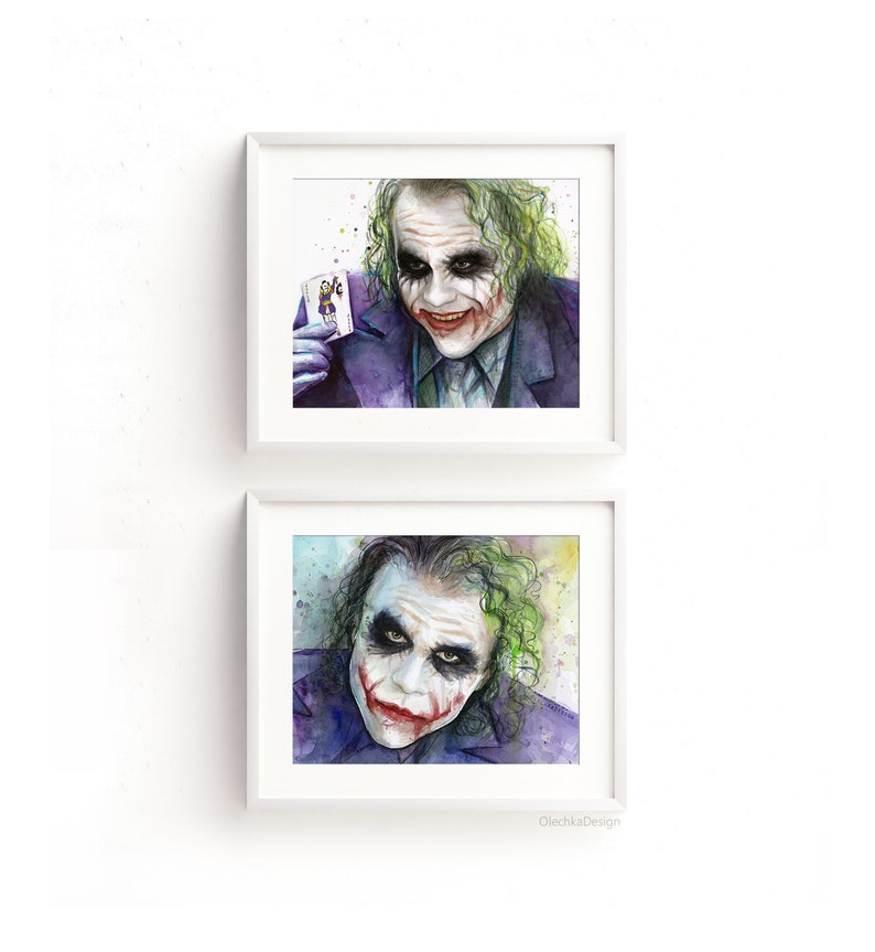 May include: Two framed watercolor paintings of the Joker from the movie The Dark Knight. The Joker is depicted with a green and purple background and a sinister smile. The top painting shows the Joker holding a playing card. The bottom painting shows the Joker looking directly at the viewer.