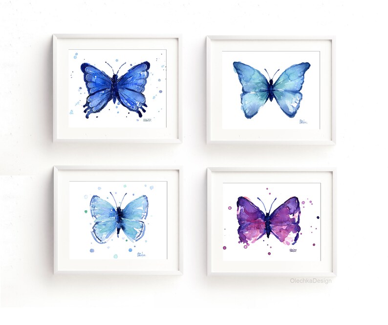 May include: Set of four watercolor paintings of butterflies in shades of blue and purple. Each butterfly is surrounded by small white dots on a white background. The paintings are framed in white frames.