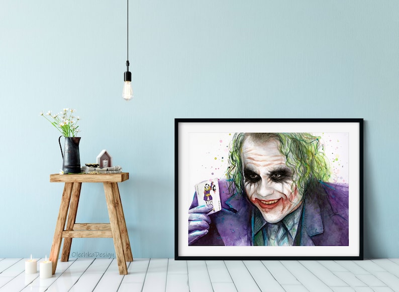May include: A watercolour painting of the Joker from the film "The Dark Knight". He is holding a playing card with the Joker on it and has a sinister smile on his face.