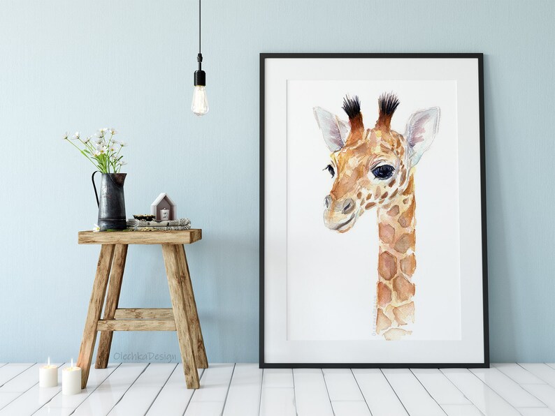 May include: A watercolor painting of a baby giraffe with brown and white spots. The giraffe is looking to the left and has a sweet expression on its face. The painting is framed in a black frame.