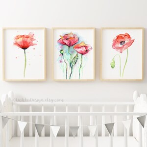 May include: Three framed watercolor paintings of red poppies with green stems and leaves. The paintings are displayed on a white wall above a white crib with a gray bunting.