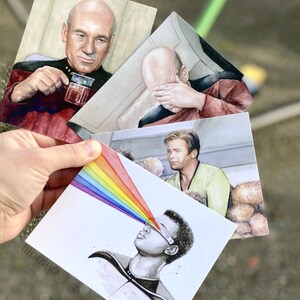 May include: Four watercolor illustrations of Star Trek characters. The first shows Captain Picard drinking tea, the second shows Captain Picard with his hand over his eyes, the third shows a character with a rainbow emanating from their eyes, and the fourth shows a character with a rainbow emanating from their eyes.