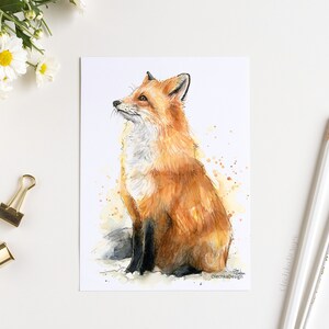 May include: Watercolor painting of a red fox sitting on a white background with brown watercolor splatters. The fox is looking up and has a bushy tail.