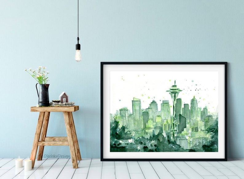 May include: A watercolor painting of the Seattle skyline in shades of green. The Space Needle is the tallest building in the painting, and the other buildings are clustered around it. The painting is set against a white background.