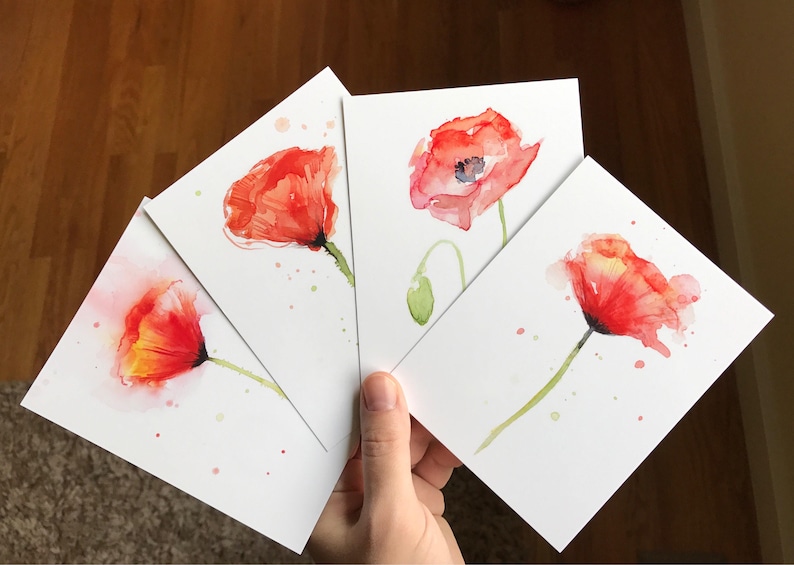 May include: Four watercolor paintings of red poppies on white card stock. Each painting features a single poppy with a green stem and leaves.