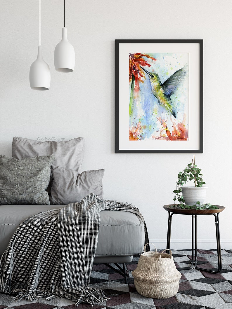 May include: Watercolor painting of a hummingbird in flight, drinking nectar from a red flower. The background is a soft blue with splashes of color.