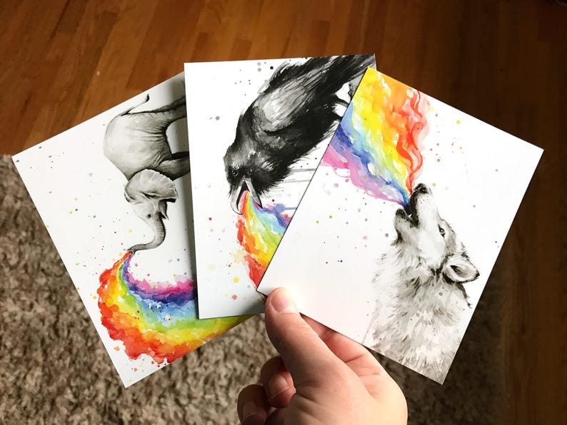 May include: Three watercolor paintings on white cardstock. Each painting features a different animal: an elephant, a raven, and a wolf. Each animal is blowing a rainbow out of its mouth.