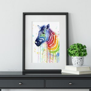 May include: A watercolor painting of a zebra with a rainbow pattern on its stripes. The zebra is facing to the left and has a white background. The painting is framed in a black frame.