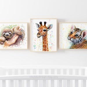 May include: Three watercolor paintings of baby animals in frames. The first painting features a sloth with a green background. The second painting features a giraffe with a white background and colorful dots. The third painting features a tiger with a white background and colorful dots.