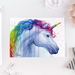May include: Watercolor painting of a unicorn with a rainbow mane and horn. The unicorn is facing to the right and has a white body with blue and purple hues. The background is white with light pink and blue watercolor splatters.