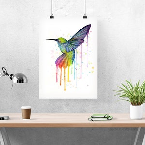 May include: A watercolor painting of a hummingbird in flight with a rainbow of colors dripping from its wings. The background is white with a few scattered paint splatters.