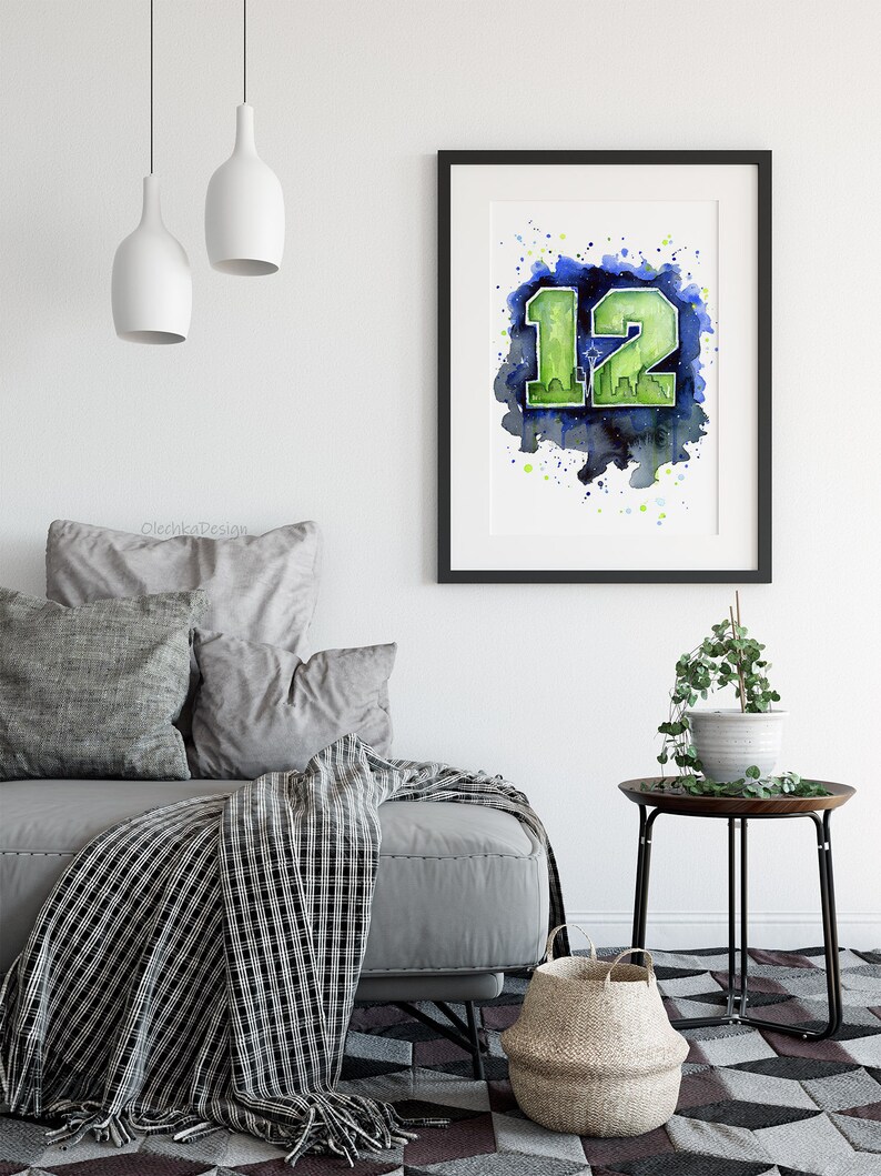 May include: Framed watercolor art print featuring the number 12 in green, with a cityscape silhouette, set against a blue and green watercolor background. The artwork is displayed in a black frame, suitable for home decor.