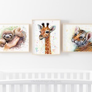 May include: Three watercolor paintings of baby animals in frames. The first painting features a sloth with a green background. The second painting features a giraffe with a white background and colorful dots. The third painting features a tiger with a white background and colorful dots.