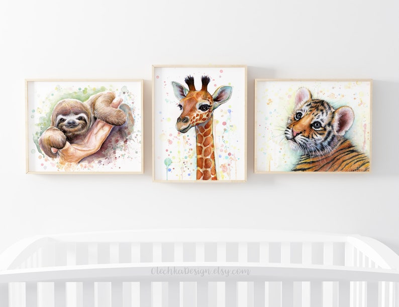 May include: Three watercolor paintings of baby animals in frames. The first painting features a sloth with a green background. The second painting features a giraffe with a white background and colorful dots. The third painting features a tiger with a white background and colorful dots.